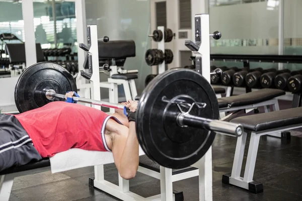 Muscular man lifting barbell on bench — Stock Photo, Image