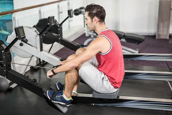 Hombre muscular en la máquina de remo — Foto de Stock