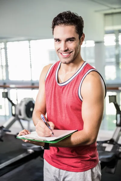 Homme souriant écrivant sur le presse-papiers — Photo