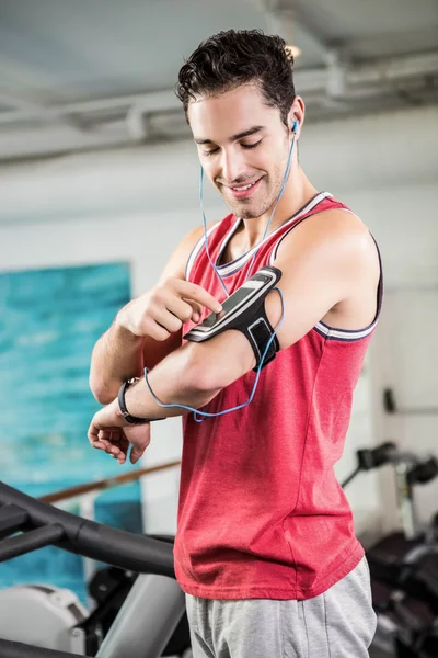 Sonriente hombre en la cinta de correr con el teléfono inteligente — Foto de Stock