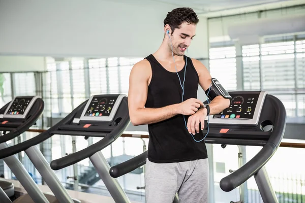 Sonriente hombre en la cinta de correr usando reloj inteligente — Foto de Stock