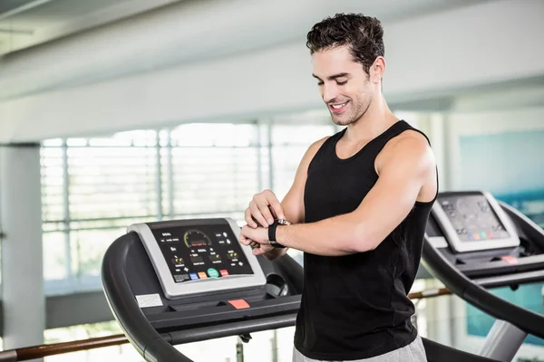 Smiling man on treadmill using smart watch — Stock Photo, Image