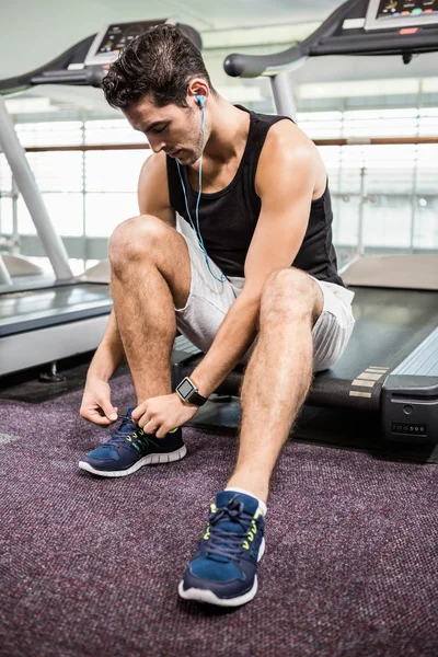 Fit man sitting on treadmill and tying the shoelace — Stock Photo, Image