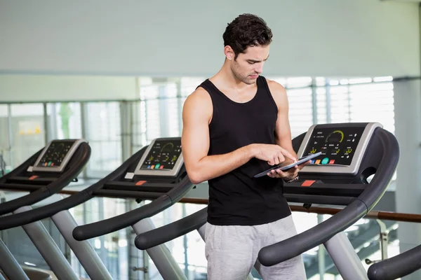 Hombre serio en la cinta de correr de pie con la tableta — Foto de Stock