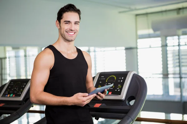 Sonriente hombre en la cinta de correr celebración tableta — Foto de Stock