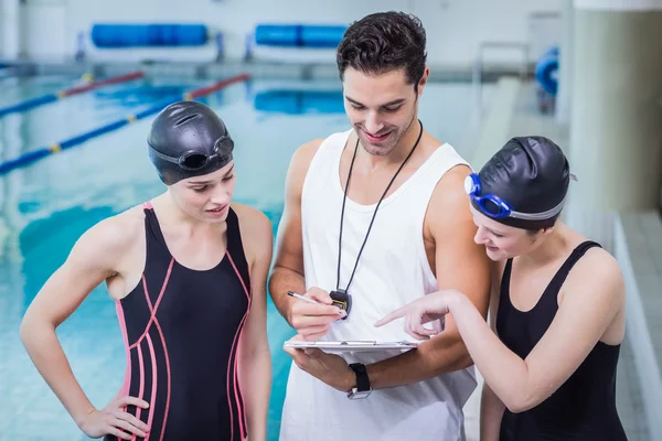 Trainer sorridente che mostra appunti ai nuotatori — Foto Stock