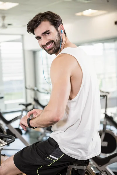 Uomo sorridente in cyclette con smartwatch — Foto Stock