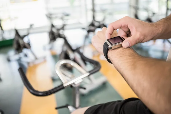 Close up of man using smartwatch on exercise bike — Stock Photo, Image