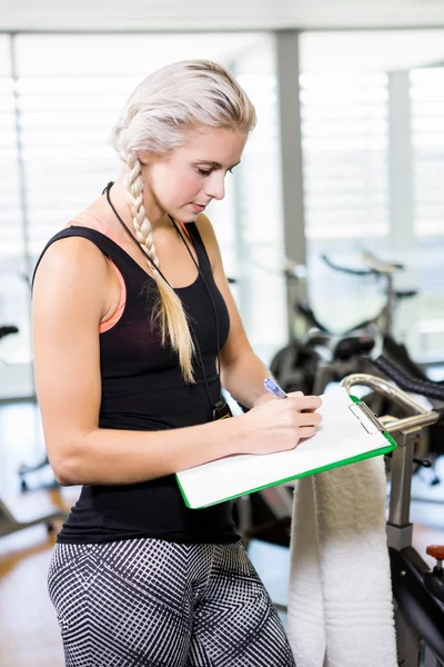 Entrenadora sonriente escribiendo en portapapeles —  Fotos de Stock