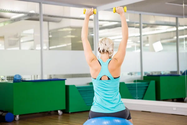 Fit mujer levantando pesas y sentado en la bola de ejercicio —  Fotos de Stock