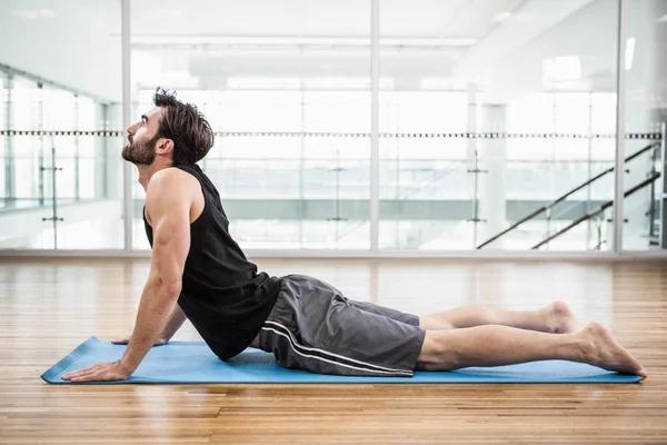 Handsome man on cobra pose on the mat — Stock Photo, Image