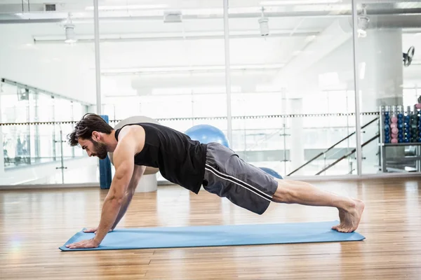 Homem muscular fazendo empurrar para cima no tapete — Fotografia de Stock