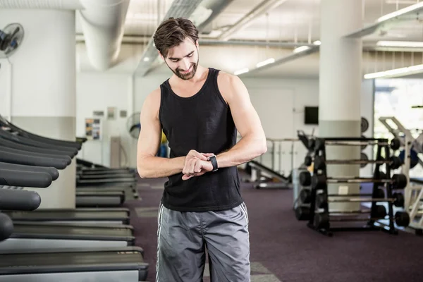 Lächelnder Mann auf dem Laufband mit Blick auf Smartwatch — Stockfoto