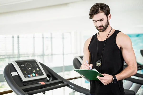 Serious trainer writing on clipboard — Stock Photo, Image