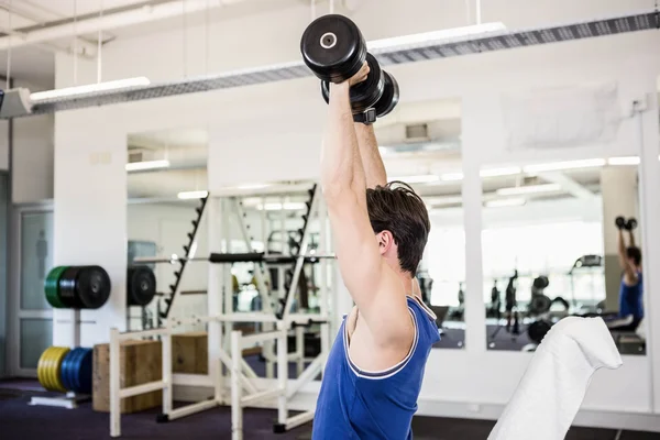 Muscular man lifting dumbbells on bench — Stock Photo, Image