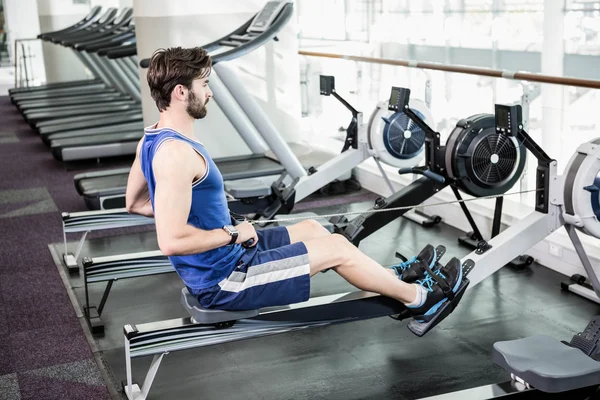 Handsome man doing exercise on drawing machine — Stock Photo, Image