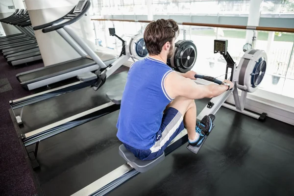 Bonito homem fazendo exercício na máquina de desenho — Fotografia de Stock