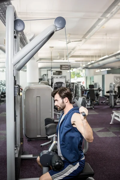 Focused man using weights machine for arms — Stock Photo, Image