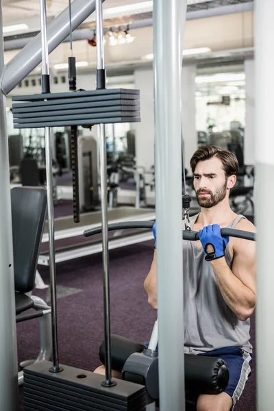 Focused man using weights machine for arms — Stock Photo, Image