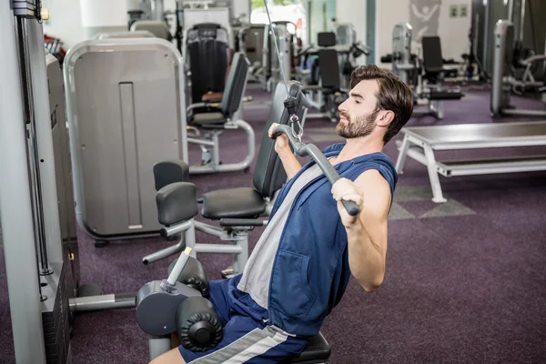 Hombre enfocado usando máquina de pesos para brazos — Foto de Stock