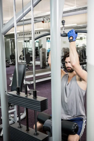 Homme focalisé utilisant la machine de poids pour les bras — Photo