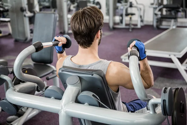 Uomo concentrato che utilizza la macchina pesi per le braccia — Foto Stock