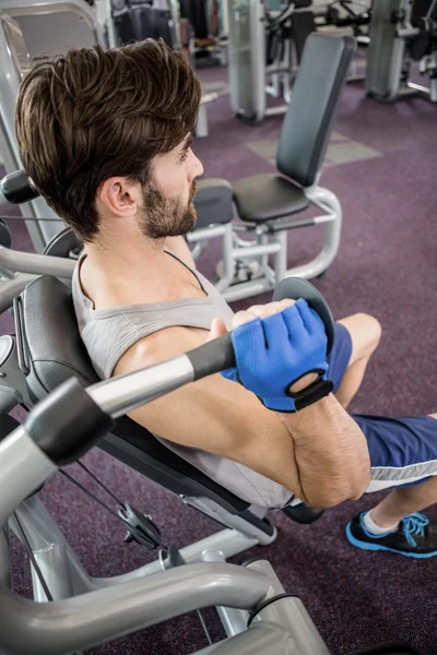 Hombre enfocado usando máquina de pesos para brazos —  Fotos de Stock