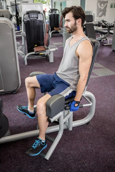 Hombre enfocado utilizando la máquina de pesos para las piernas — Foto de Stock