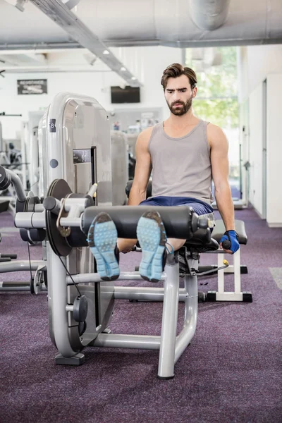 Uomo focalizzato utilizzando pesi macchina per le gambe — Foto Stock