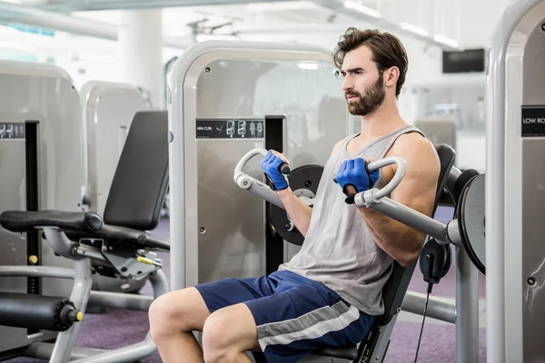 Homme focalisé utilisant la machine de poids pour les bras — Photo