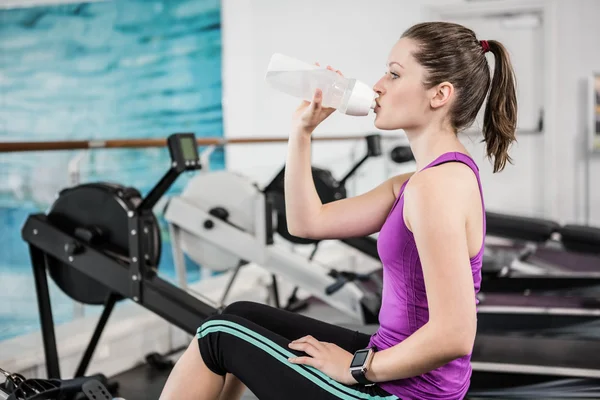 Fit brunette on drawing machine drinking — Stock Photo, Image