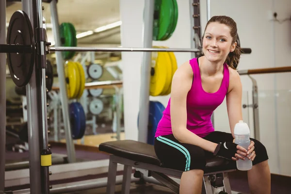 Sorrindo mulher sentada no banco barbell — Fotografia de Stock