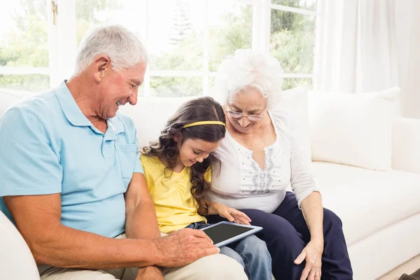 Бабушка и дедушка используют планшет со своей внучкой — стоковое фото