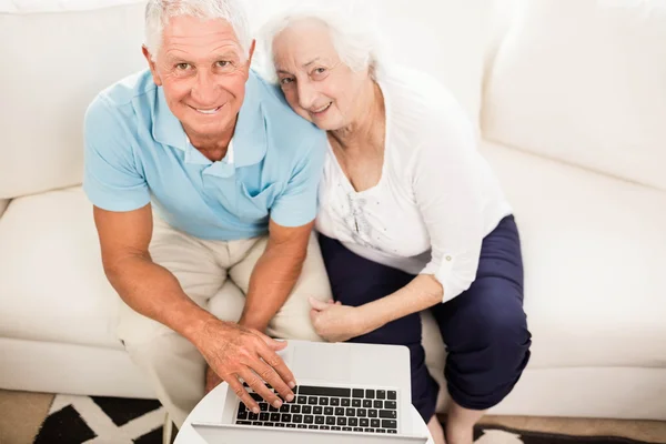 Улыбающаяся пожилая пара с помощью ноутбука — стоковое фото