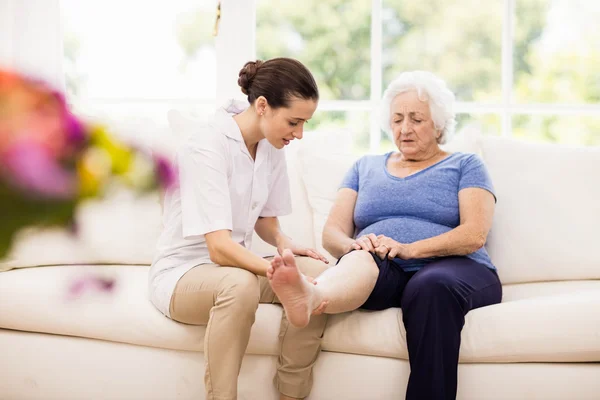 Physiotherapist taking care of sick elderly patient — Stock Photo, Image