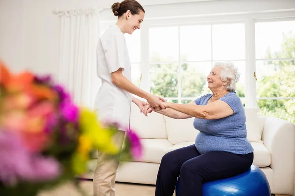 Physiotherapist taking care of sick elderly patient — Stock Photo, Image
