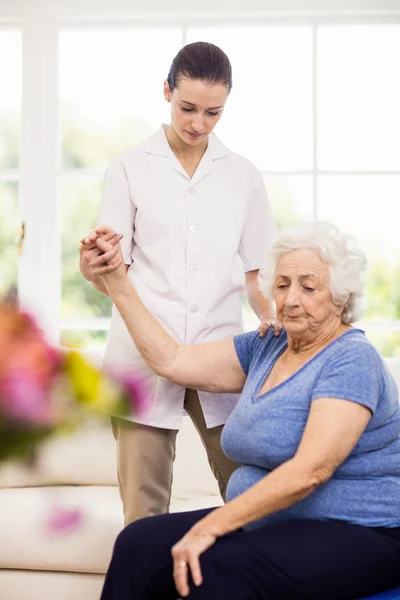 Physiotherapist taking care of sick elderly patient — Stock Photo, Image