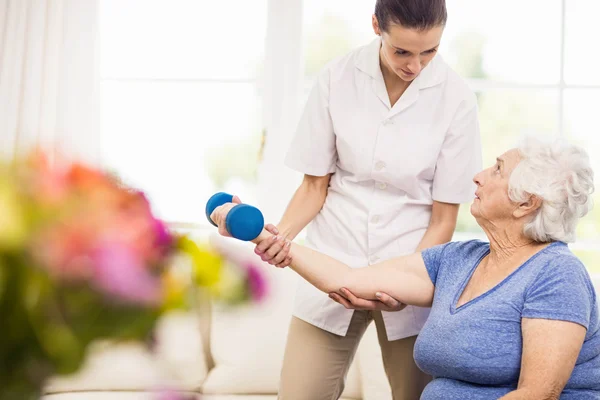 Physiotherapist taking care of sick elderly patient — Stock Photo, Image