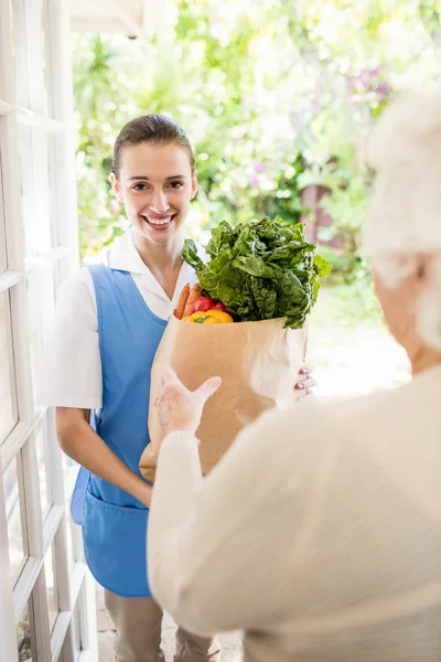 Belle infirmière apportant des légumes à un vieux patient — Photo