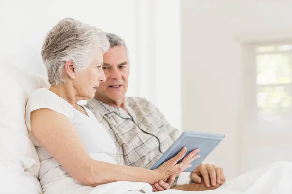 Äldre par med tablett på sängen — Stockfoto