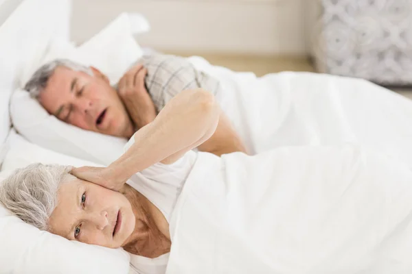 Despierta mujer mayor en la cama cubriéndose los oídos — Foto de Stock