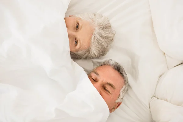 Lyckliga äldre par under täcket i sängen — Stockfoto