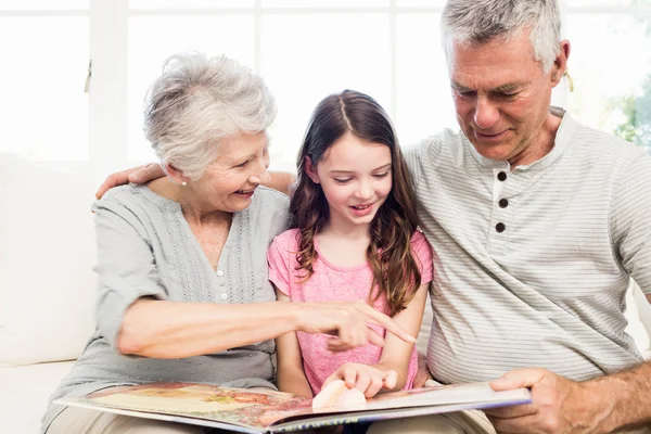 Mor-och farföräldrar med barnbarn läser en bok — Stockfoto