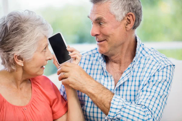 Lyckliga äldre paret lyssnar på smartphone — Stockfoto