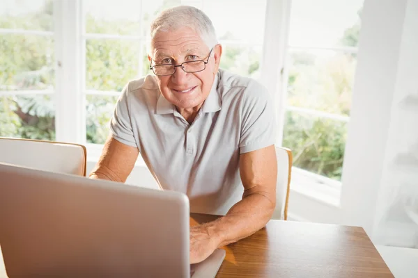 Uśmiechający się starszy człowiek korzysta z laptopa — Zdjęcie stockowe