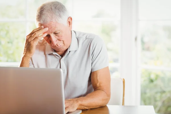 Обеспокоенный пожилой человек с помощью ноутбука — стоковое фото