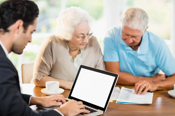 Empresario usando portátil mientras pareja de ancianos —  Fotos de Stock