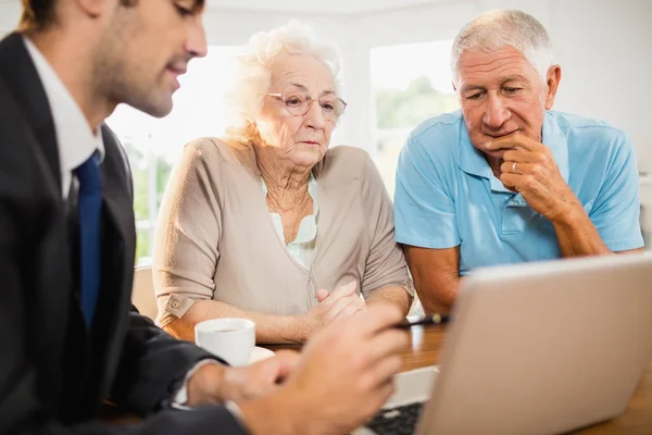 Бизнесмен показывает ноутбук пожилой паре — стоковое фото