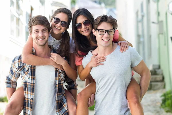 Hip men giving piggy back to their girlfriends — Stock Photo, Image