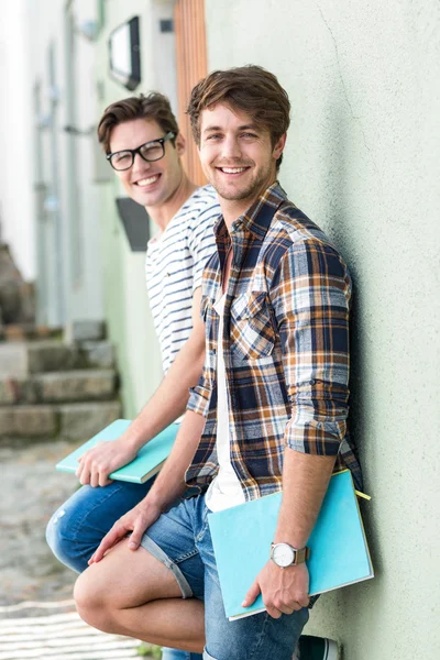 Hip mannen leunend tegen muur en houden van laptops — Stockfoto